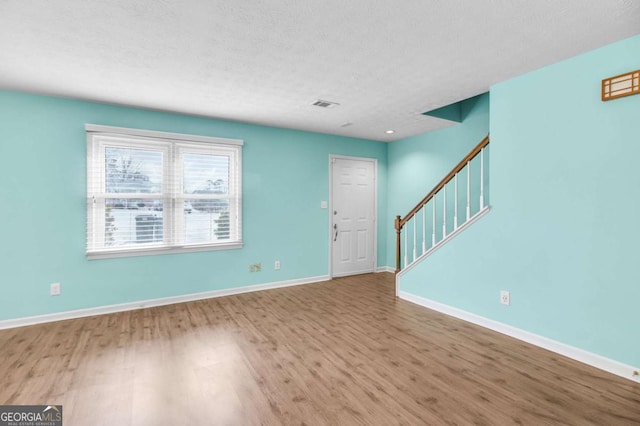 interior space with a textured ceiling and hardwood / wood-style flooring