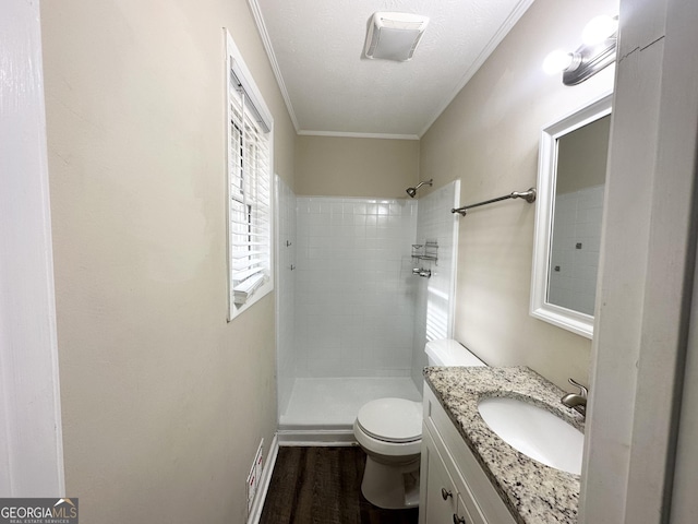 bathroom with tiled shower, toilet, hardwood / wood-style floors, and ornamental molding