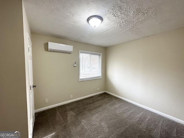 empty room featuring dark carpet, an AC wall unit, and a textured ceiling