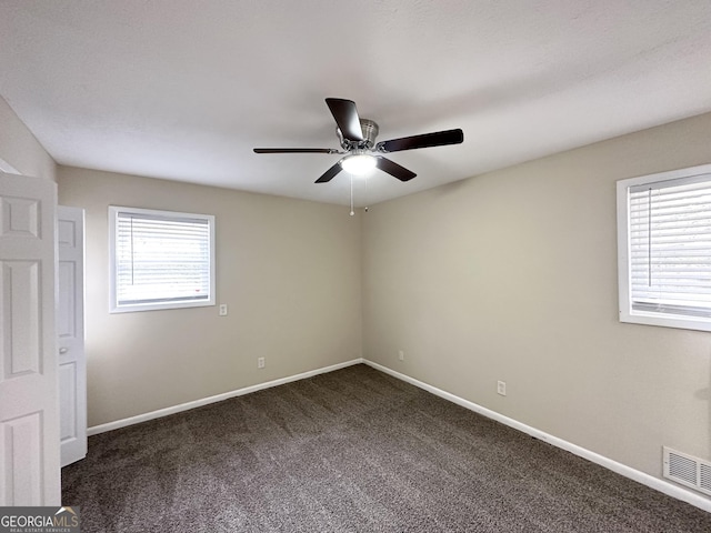 spare room with dark carpet, plenty of natural light, and ceiling fan