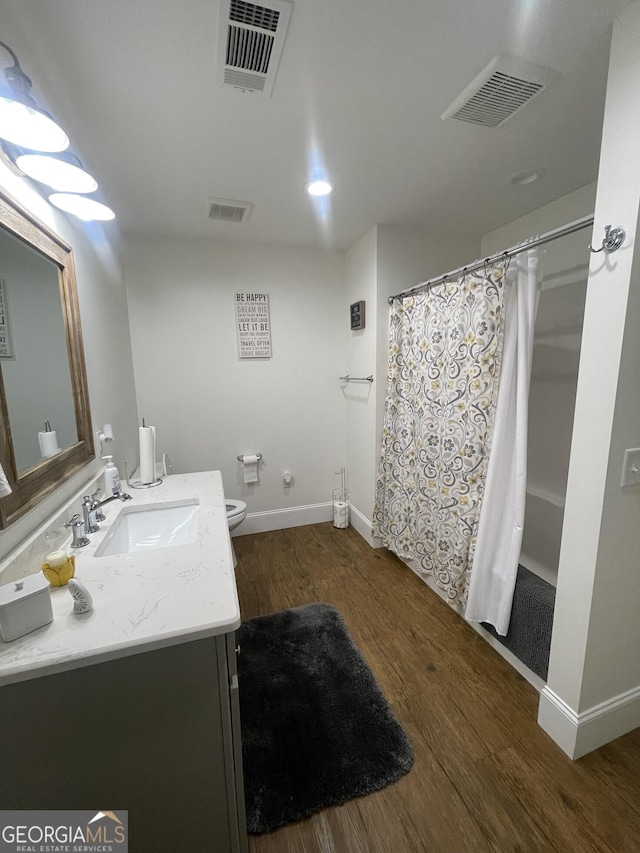 bathroom featuring walk in shower, hardwood / wood-style floors, vanity, and toilet