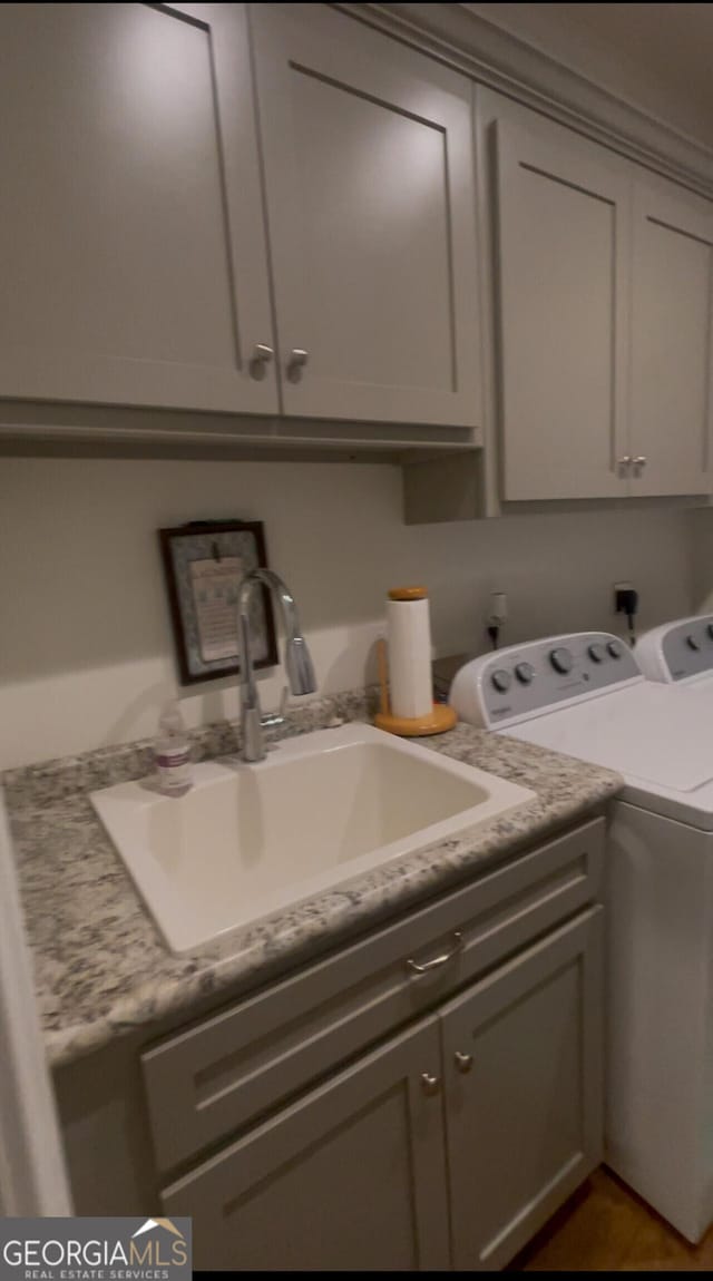 laundry room featuring washer and clothes dryer, sink, and cabinets