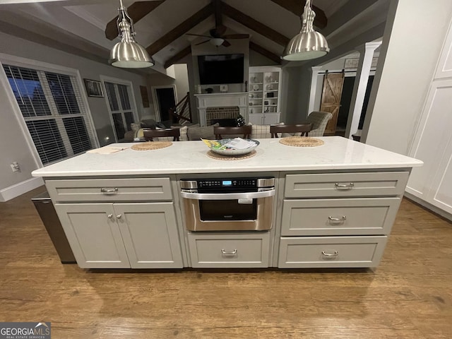 kitchen featuring a barn door, stainless steel oven, a center island, and vaulted ceiling with beams