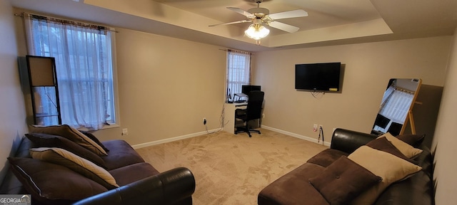 carpeted living room featuring a tray ceiling and ceiling fan