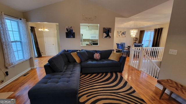 living room featuring a chandelier, wood-type flooring, and lofted ceiling