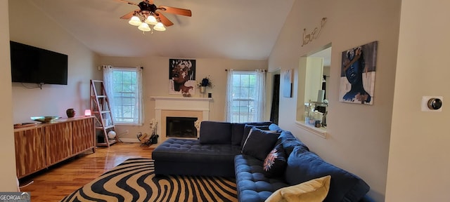 living room featuring ceiling fan, light hardwood / wood-style floors, and vaulted ceiling