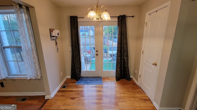 entryway with french doors, light hardwood / wood-style floors, and a notable chandelier