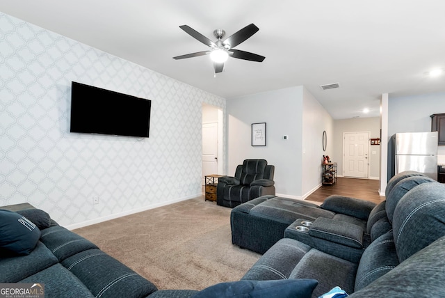 living room with visible vents, wallpapered walls, ceiling fan, carpet, and baseboards