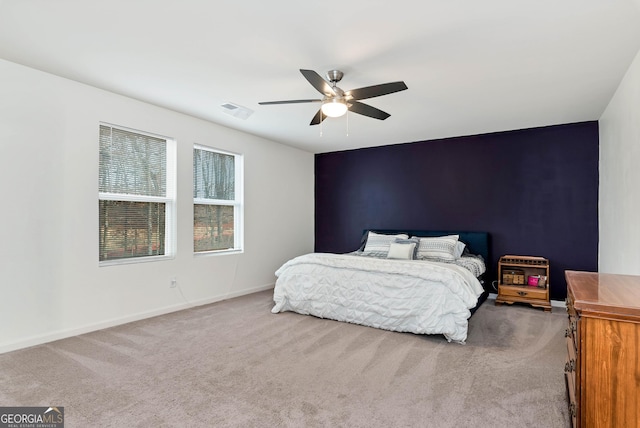 bedroom with visible vents, carpet flooring, baseboards, ceiling fan, and an accent wall