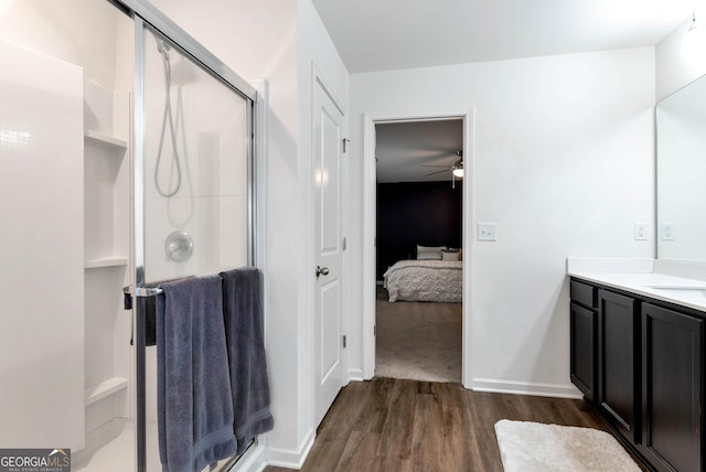 ensuite bathroom with vanity, wood finished floors, baseboards, a stall shower, and connected bathroom