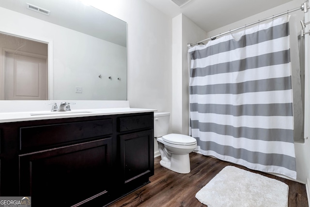 bathroom with visible vents, toilet, curtained shower, wood finished floors, and vanity