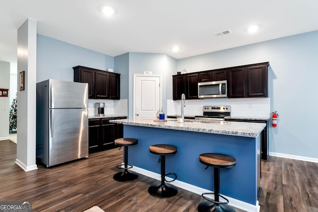 kitchen with light stone counters, visible vents, appliances with stainless steel finishes, and dark wood-style flooring