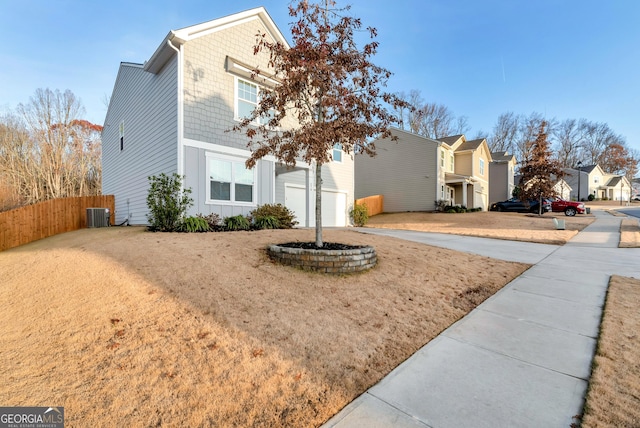 traditional-style home with a residential view, central AC, concrete driveway, and fence