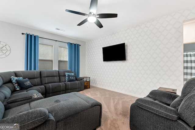 living room featuring visible vents, a ceiling fan, wallpapered walls, baseboards, and light colored carpet