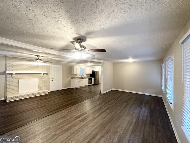 unfurnished living room with a fireplace, dark hardwood / wood-style flooring, a textured ceiling, and sink