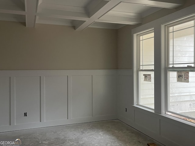 spare room with coffered ceiling, beam ceiling, and concrete flooring