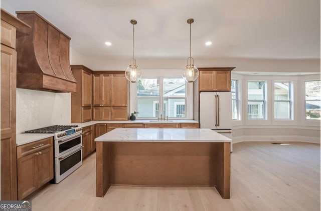 kitchen featuring high quality appliances, a wealth of natural light, and light hardwood / wood-style flooring