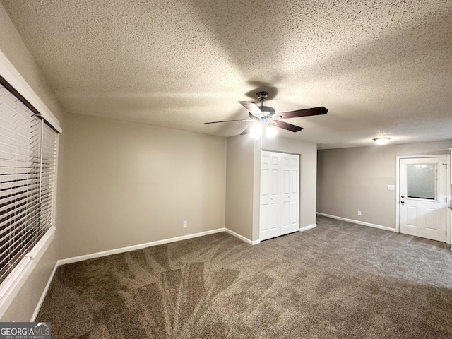 unfurnished bedroom featuring dark colored carpet, a textured ceiling, a closet, and ceiling fan