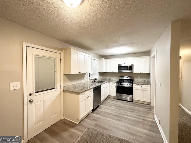 kitchen featuring light stone countertops, sink, white cabinets, and stainless steel appliances