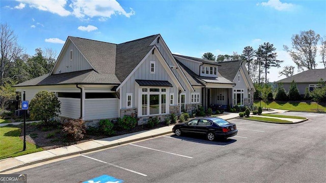 view of front of house with uncovered parking, stone siding, and board and batten siding