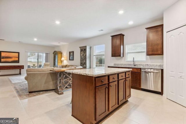 kitchen featuring light stone countertops, sink, light tile patterned floors, dishwasher, and a kitchen island