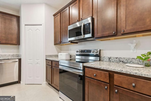 kitchen with light stone counters, light tile patterned floors, and stainless steel appliances