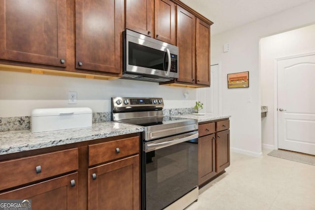 kitchen with light stone counters and appliances with stainless steel finishes