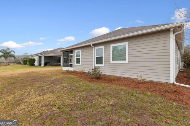 back of house with a sunroom and a lawn
