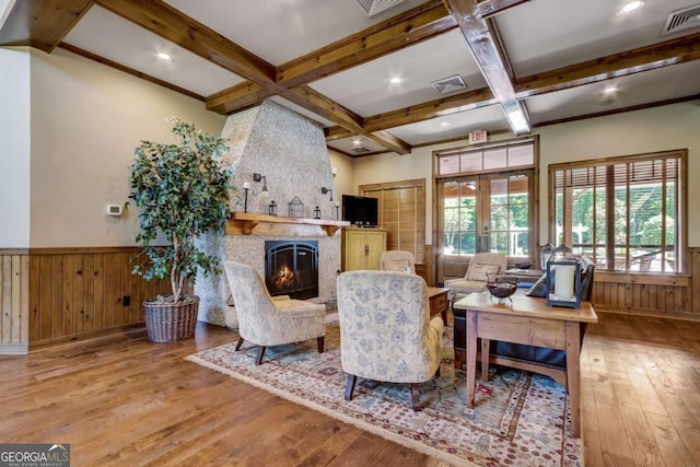 living room with a large fireplace, light wood-type flooring, wooden walls, and french doors