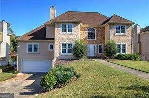 view of front of house with a front yard, concrete driveway, a chimney, and an attached garage