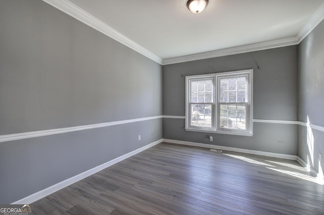 spare room featuring ornamental molding, baseboards, and wood finished floors