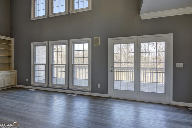 interior space featuring plenty of natural light, a towering ceiling, and wood finished floors