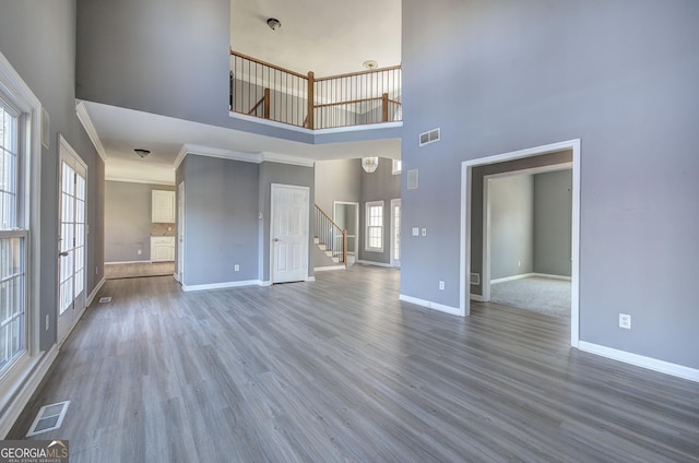 unfurnished living room featuring visible vents, stairway, and wood finished floors