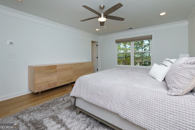 bedroom with ceiling fan, ornamental molding, and hardwood / wood-style flooring