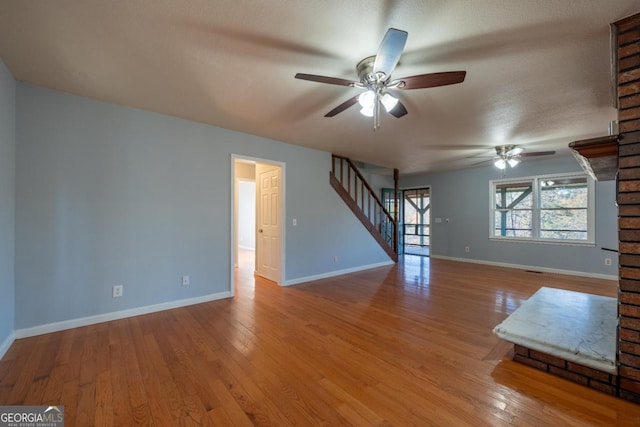 unfurnished living room with ceiling fan, a textured ceiling, and light hardwood / wood-style flooring