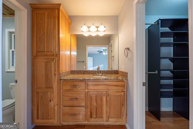 bathroom featuring hardwood / wood-style flooring, vanity, ceiling fan, and toilet