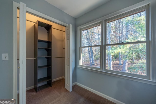 unfurnished bedroom featuring dark colored carpet and multiple windows