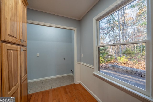 clothes washing area with crown molding, plenty of natural light, cabinets, and light wood-type flooring