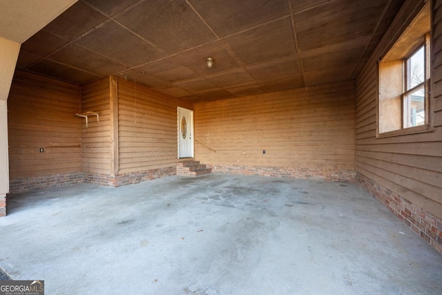 exterior space with wooden walls, concrete floors, and brick wall