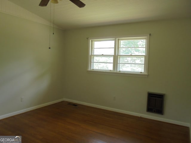 spare room with dark hardwood / wood-style flooring, heating unit, and ceiling fan