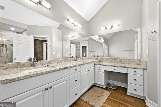 bathroom with wood-type flooring, vanity, vaulted ceiling, and an enclosed shower