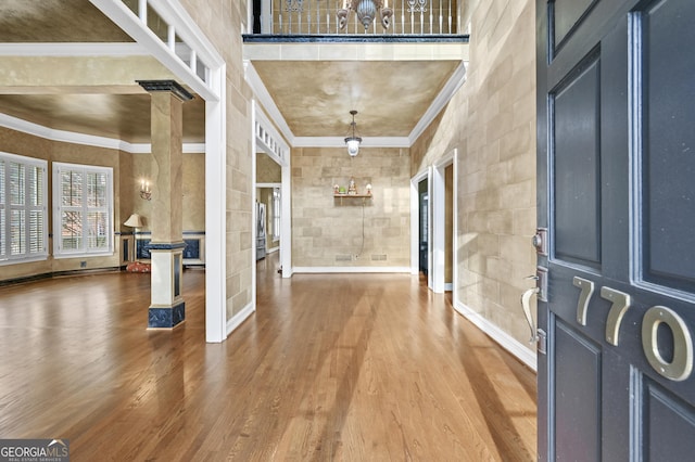 entryway with hardwood / wood-style floors, a towering ceiling, and ornamental molding