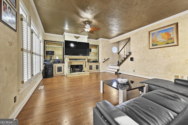 living room with hardwood / wood-style floors, plenty of natural light, crown molding, and a premium fireplace