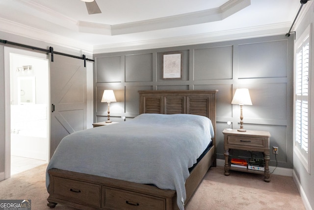 carpeted bedroom with a barn door, a raised ceiling, ceiling fan, and crown molding