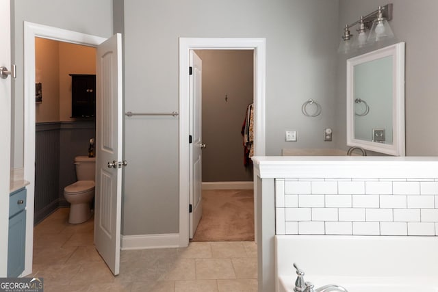 bathroom featuring tile patterned floors, vanity, toilet, and a washtub