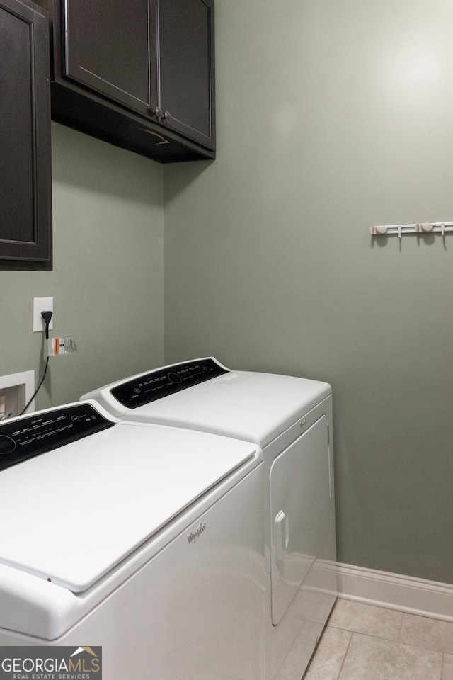 laundry area featuring washer and clothes dryer, light tile patterned floors, and cabinets