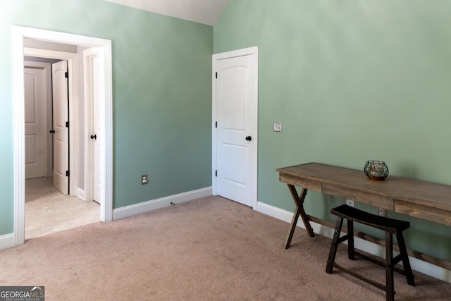 carpeted office space featuring vaulted ceiling