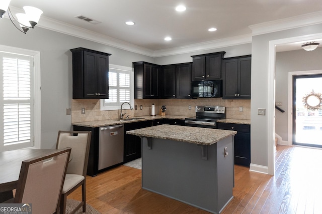 kitchen with decorative backsplash, stainless steel appliances, sink, light hardwood / wood-style flooring, and a kitchen island