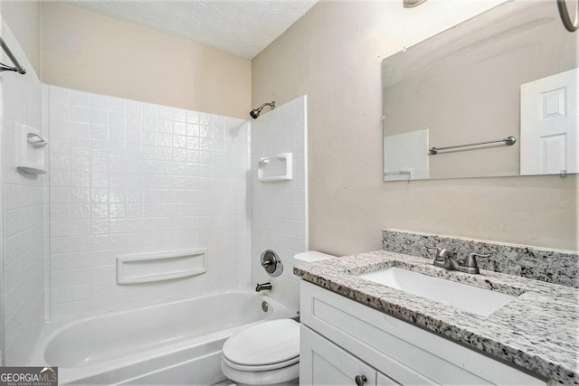 full bathroom featuring tiled shower / bath, vanity, a textured ceiling, and toilet