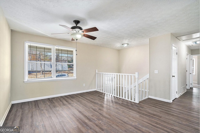 empty room with dark hardwood / wood-style floors, ceiling fan, and a textured ceiling